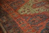 Intricate handwoven detail of an antique Soumac carpet with rich red and green geometric patterns.