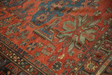 Textured weave of an antique Soumac carpet with jade green starburst motifs on a madder red ground.
