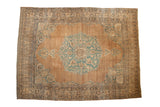 Antique Kerman carpet featuring a scalloped blue medallion on a tea-washed field with arabesque spandrels.