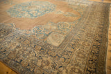 Angled view of an antique Kerman carpet's corner showing the arabesque spandrels and detailed lotus vine border.
