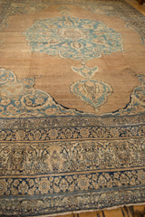 Abrashed sandalwood field of an antique Kerman carpet framed by a detailed navy and ivory lotus border.