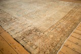 Angled corner view of an antique Kerman carpet showing the detailed palmette border and time-softened pile.