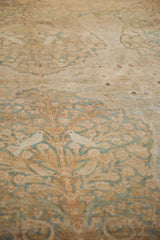 Ivory love birds perched within the Tree of Life design of a distressed Kerman carpet.