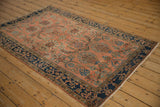 Antique Mohajeran Sarouk rug corner: indigo border, blush field with horseshoe floral arabesques.