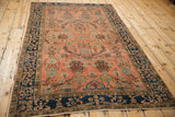Antique Mohajeran Sarouk rug corner: deep indigo border, blush field with horseshoe floral arabesques.