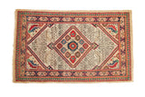 Vintage Serab rug with a red and blue serrated diamond medallion on a geometric ivory field.