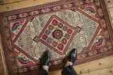 Vintage Serab rug seen from above, with a serrated diamond medallion on a geometric ivory field.