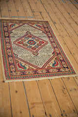 Angled view of a vintage Serab rug showing its serrated diamond medallion and colorful geometric borders.