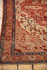 Antique Malayer rug corner: sapphire blue border, ruby red sprawling vine patterns.