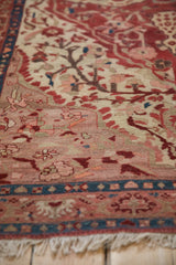 Antique Malayer rug's cream fringe, sapphire blue geometric border, and ruby red blossoming vines.