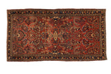 Vintage Sarouk Persian runner with floral sprays on a brick red field with a dark navy blue border.