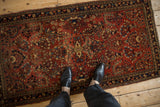 Vintage Sarouk rug runner with floral bouquets in brick red and navy, shown on a floor for scale.