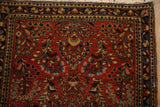Corner detail of a vintage Sarouk rug with its navy floral border and soft, even wool pile.