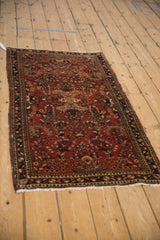 Vintage Sarouk rug runner with floral bouquets on a brick red field, shown in a full angled view.