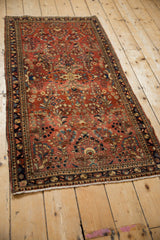 Angled view of a vintage Sarouk runner with traditional floral sprays and a dark navy border.