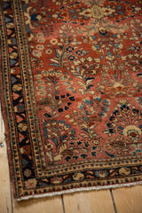 Corner view of a vintage Sarouk rug highlighting the short pile and traditional floral borders.