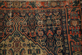 Antique Senneh rug corner with navy Herati field and pale brick red geometric vine border.