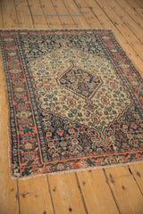 Antique Persian Senneh rug corner, highlighting geometric vine border in navy, brick red, ivory.