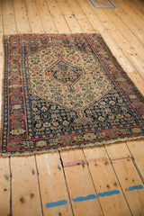 Antique Senneh rug's corner, navy blue geometric vine border, pale brick red, worn fringe.