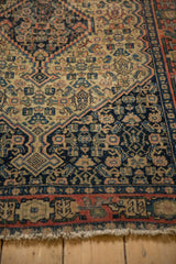 Antique Senneh rug's geometric border, featuring navy, brick red, and ivory hues with even wear.