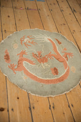 The antique round rug's pictorial dragon design and low pile seen from an angle.