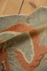 Detail of the folded Art Deco rug showing its low, hand-knotted pile in terracotta and silver.