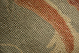 The antique rug's hand-knotted pile shows mostly even wear to the knot heads.