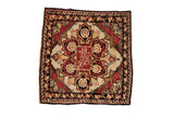 Antique Yezd square rug with a starburst medallion, red inscription, and dark vine border on an ivory ground.
