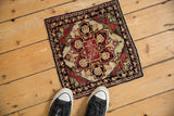 Antique Persian Yezd rug mat with a red starburst medallion, shown for scale.