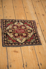Angled view of the antique Yezd square rug, showcasing its red and ivory starburst medallion.