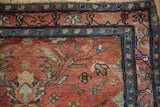 Close-up of the vintage Lilihan rug corner showing the stylized blue boteh border and cranberry red field.