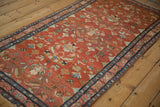 Angled view of the vintage Lilihan rug's abrashed red field and scrolling floral pattern.