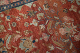 The mostly even wear and fine floral details on the abrashed red pile of a vintage Lilihan rug.