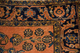 Lilihan rug corner showing dusty rose floral field and sapphire border shrimp fish motif.