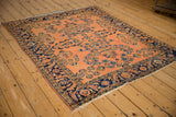 Lilihan rug corner shows dusty rose field, sapphire blue floral sprays, and navy Herati border.