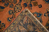 Folded Antique Lilihan rug reveals dusty rose pile, blue florals, and hand-knotted foundation.