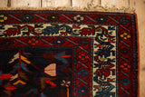 Corner of a vintage Persian Bakhtiari carpet showing its gem-toned geometric border and fringe.