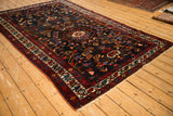 Angled view of a vintage Bakhtiari carpet showing its tree of life motifs and jewel-toned colors.