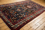 Vintage Bakhtiari carpet shown at an angle, featuring a navy field and complex gem-toned motifs.