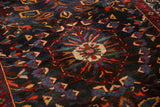 Staggered center medallion with gem-like tones on a dark navy vintage Persian Bakhtiari carpet.