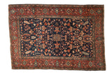 Antique Persian Farahan Sarouk rug with a floral medallion on a deep navy field and intricate red border.