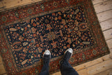 Looking down at an antique Farahan Sarouk rug, showing its intricate floral medallion and navy field.