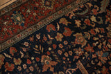 Corner detail of an antique Farahan Sarouk rug's madder red palmette border and navy blue field.