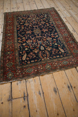 Angled view of the antique Farahan Sarouk rug highlighting its traditional navy and madder red design.