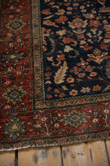 Meandering vine and palmette border beside the navy blue field of an antique Farahan Sarouk rug.