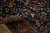 Folded corner of an antique Farahan Sarouk rug showing its rich navy field and detailed red border.