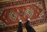 Heriz rug's geometric medallion, floral gul, and speckled yarn in brick red, cobalt blue.