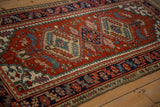 Vintage Heriz runner detail: brick red field, cobalt blue border, and beige serrated leaf designs.