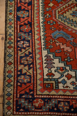 Vintage Heriz rug runner's geometric border in brick red, cobalt blue, and beige.