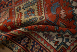 Textured pile of vintage Heriz runner, highlighting speckled brick red and blue geometric motifs.
